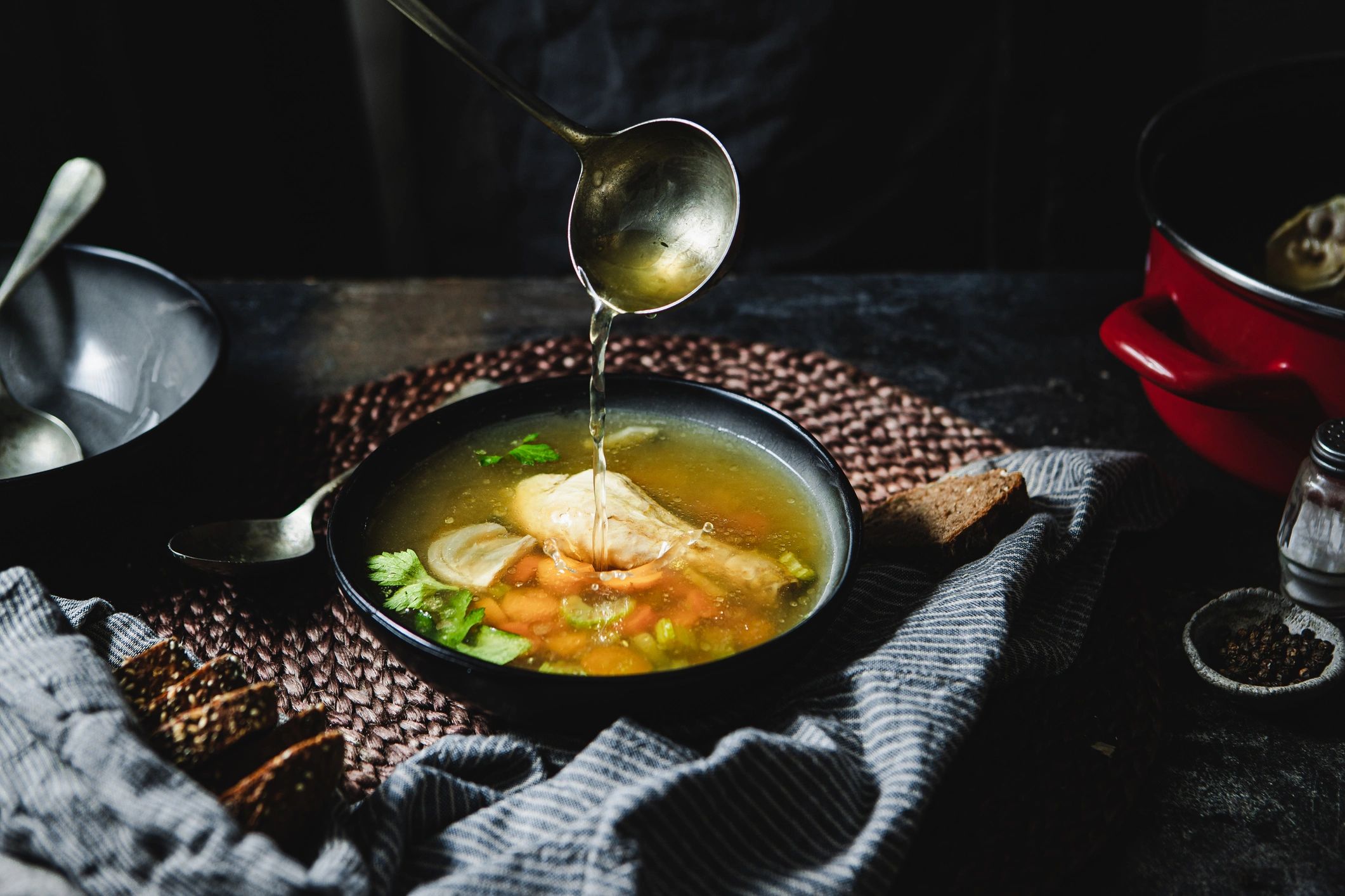 Pouring warm broth into a bowl, representing nourishing recovery routines