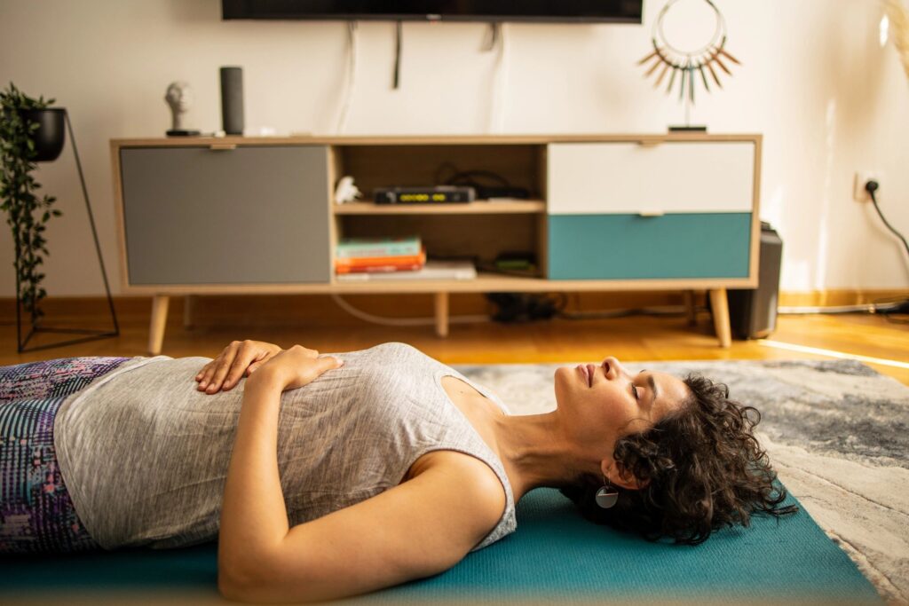 Person meditating on a yoga mat at home, practicing breathwork and nervous system regulation