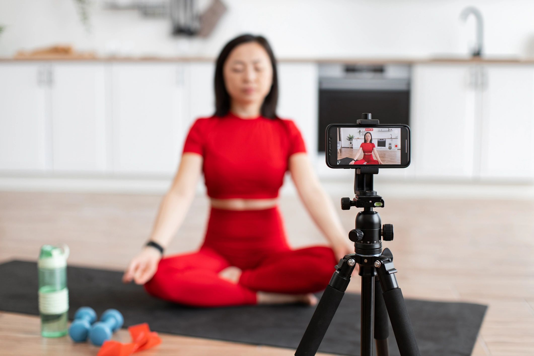 Woman meditating at home while recording a wellness video