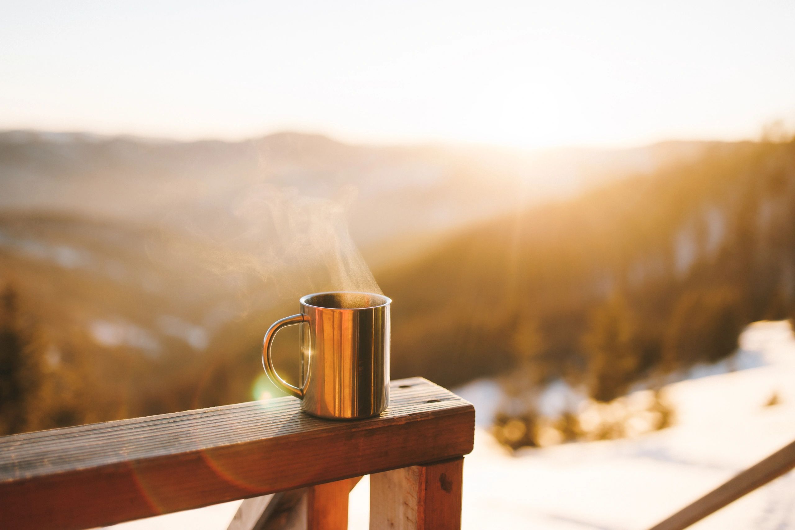 Warm mug held outdoors at sunrise suggesting restoration