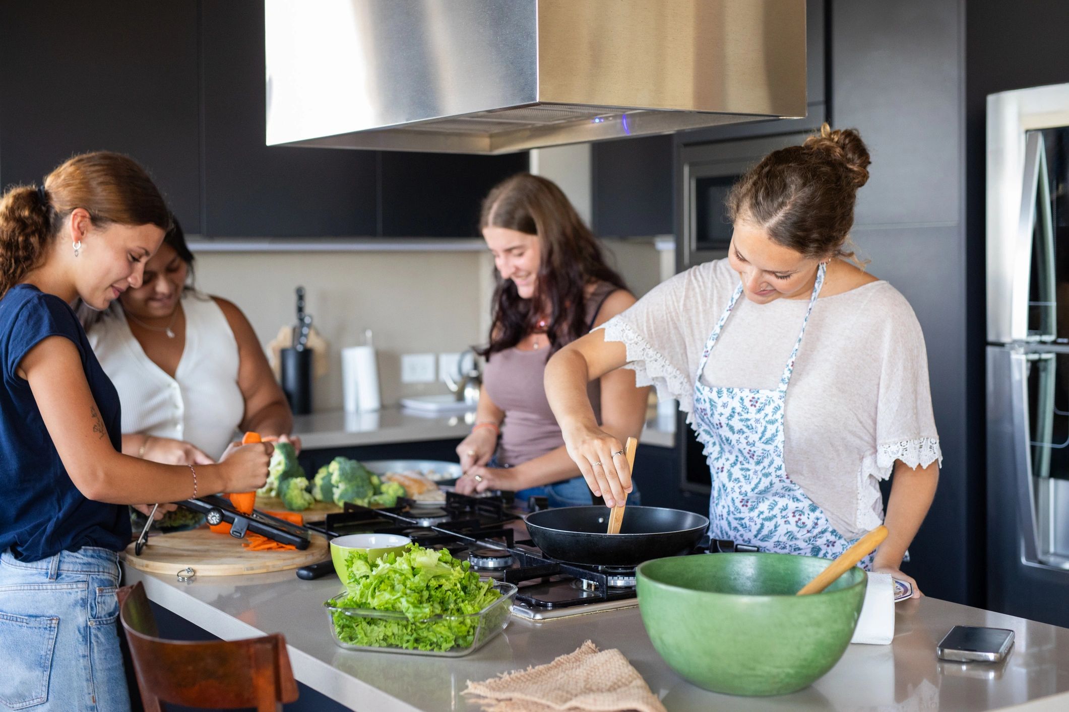 Friends preparing a fresh salad in a bright kitchen